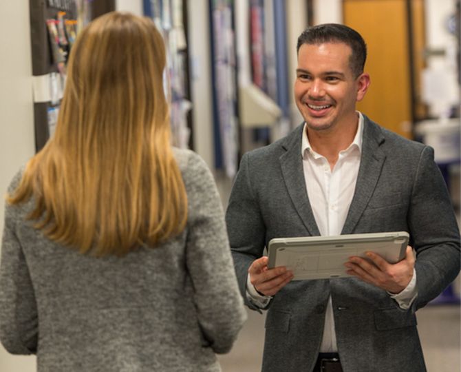 Dr. Jean Rivera Perez talks to Dr. Emily Lund while holding a tablet