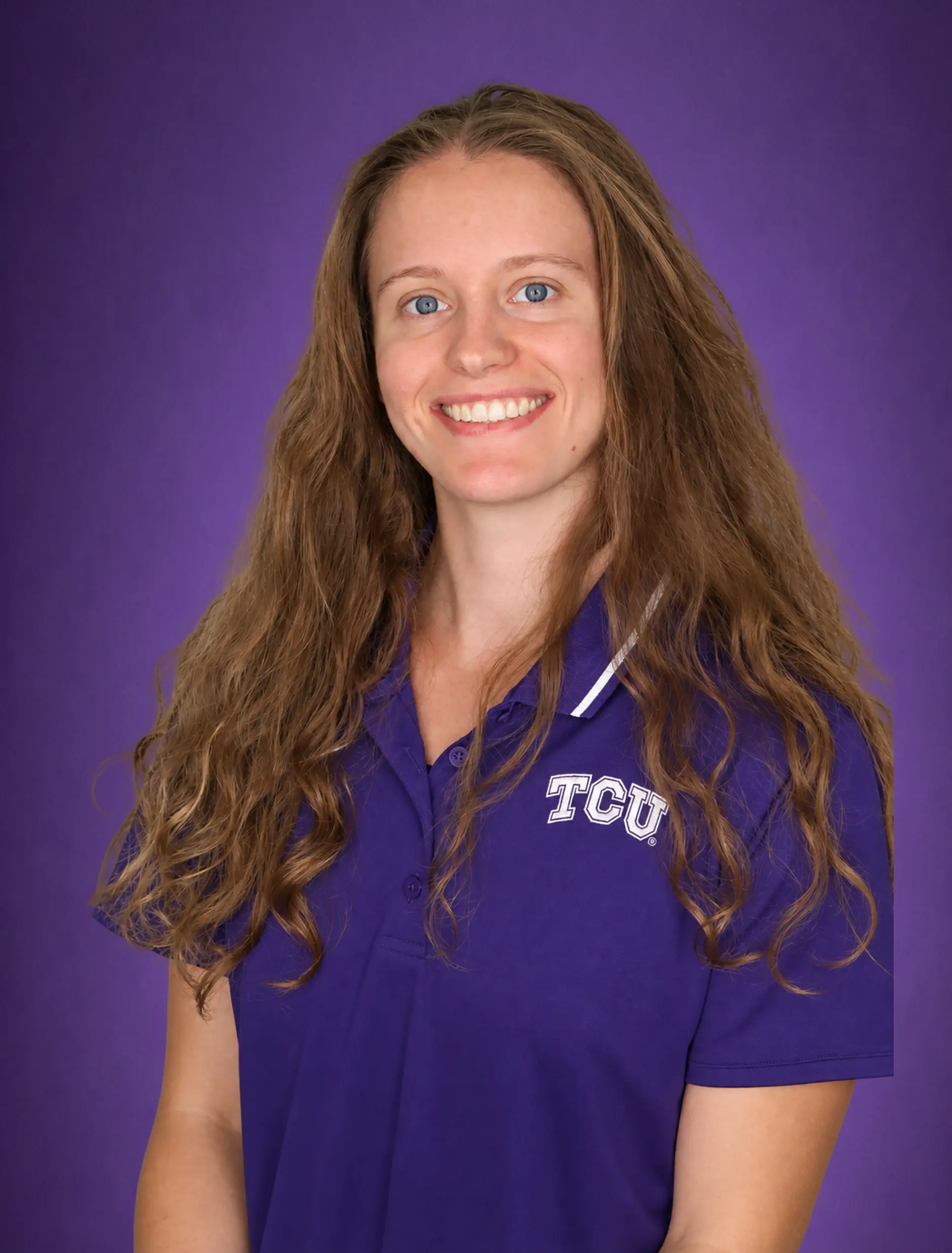 A woman smiling, wearing a purple TCU polo shirt with a purple background